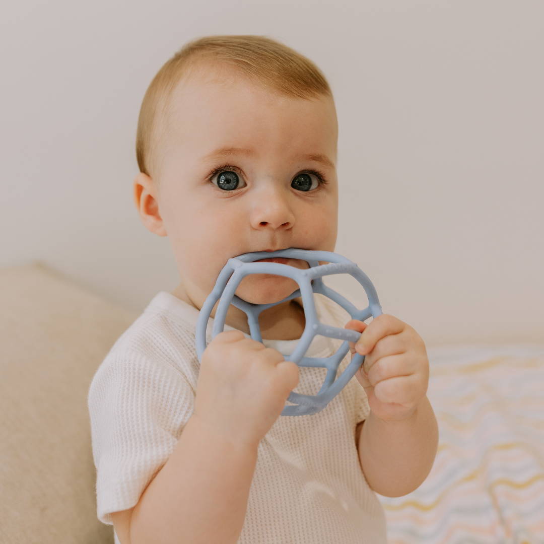 Baby boy chewing on a silicone ball