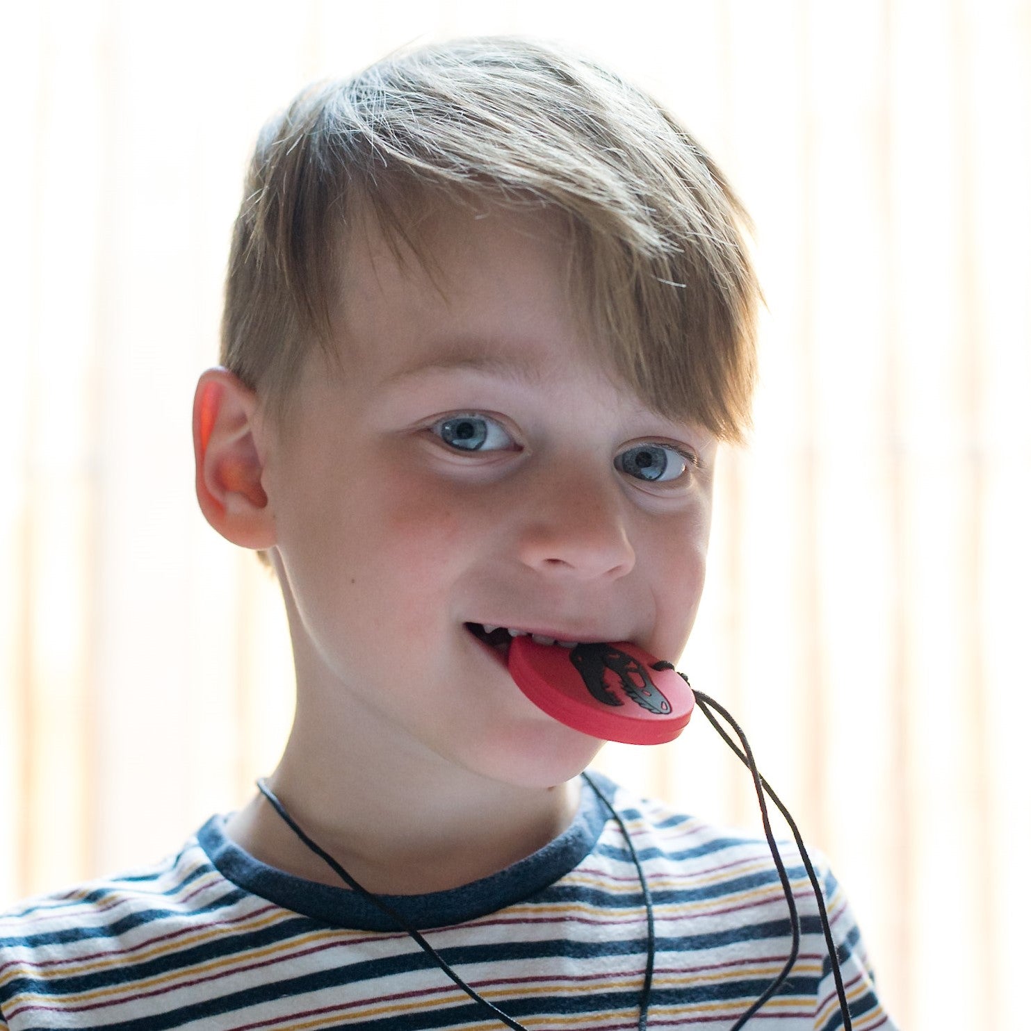 Boy chewing on dino pendant