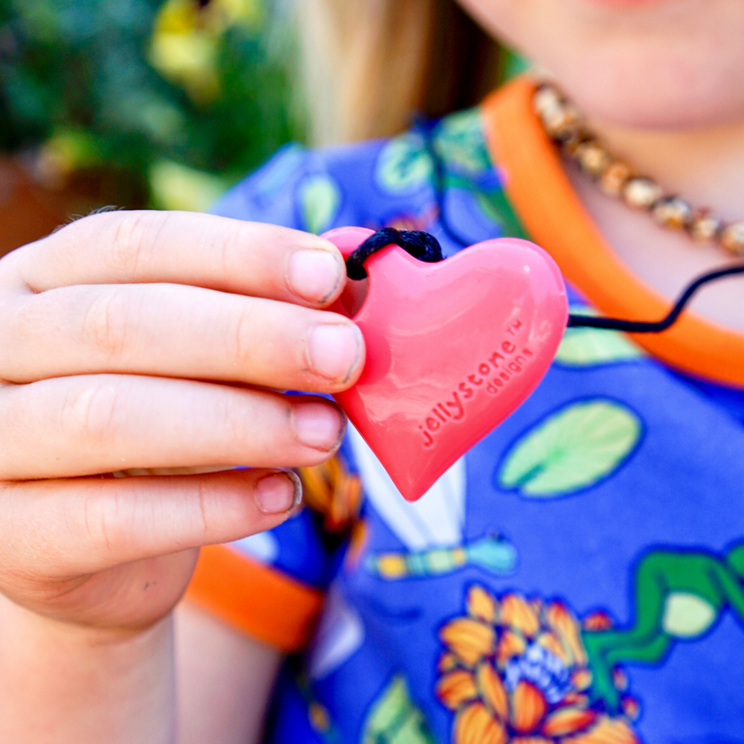 Close up of hand holding heart pendant