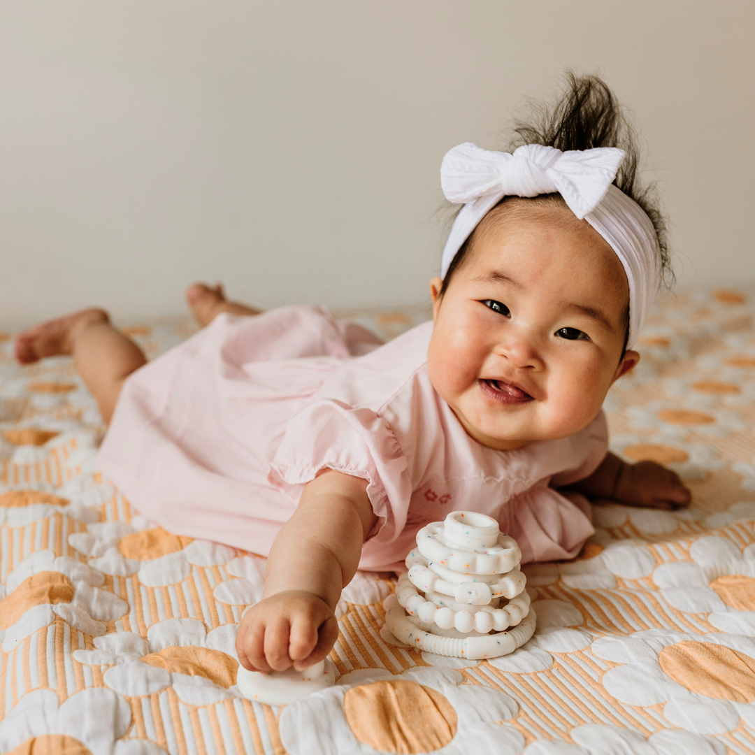 Baby girl with silicone stacker on playmat