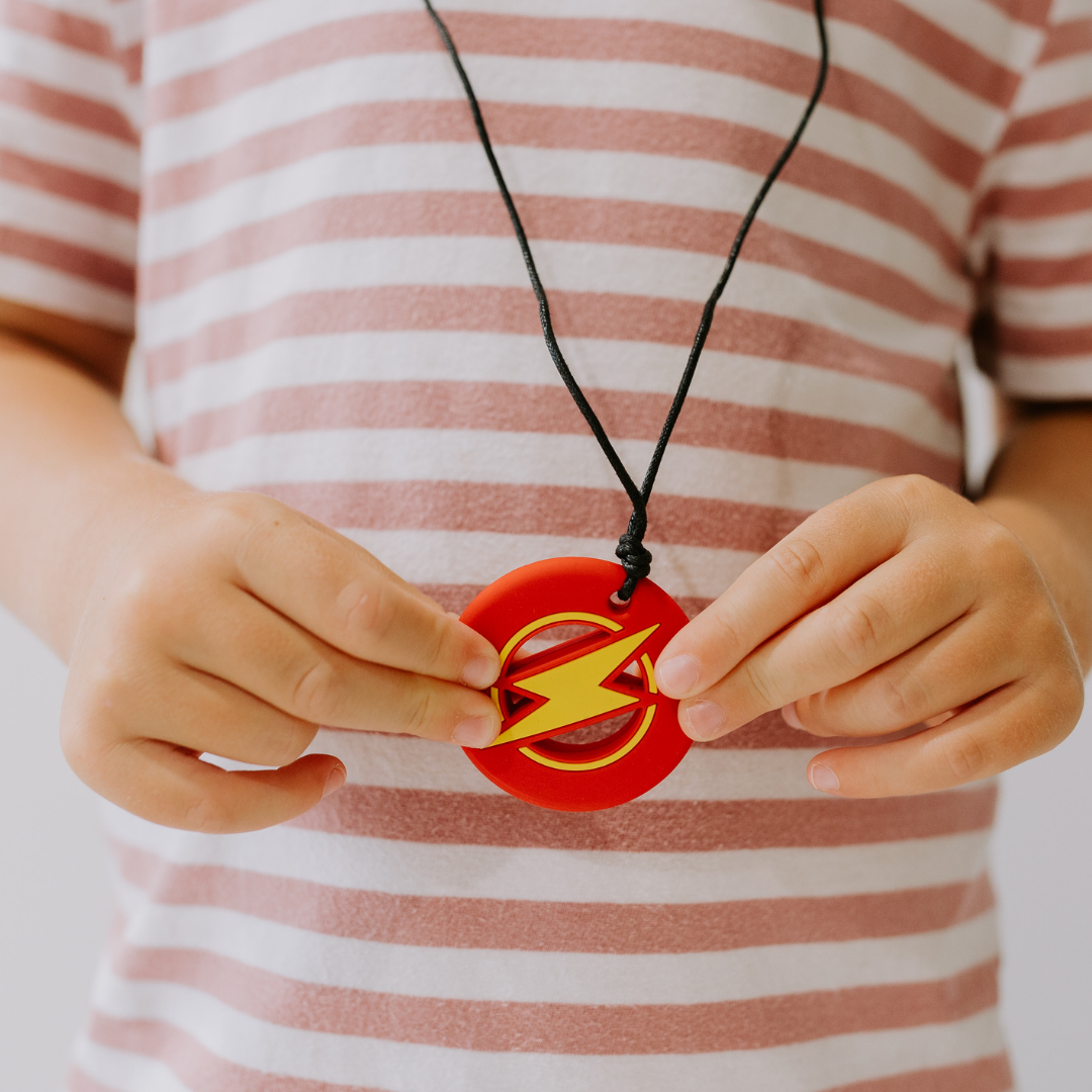 Close up of hands holding a chew pendant